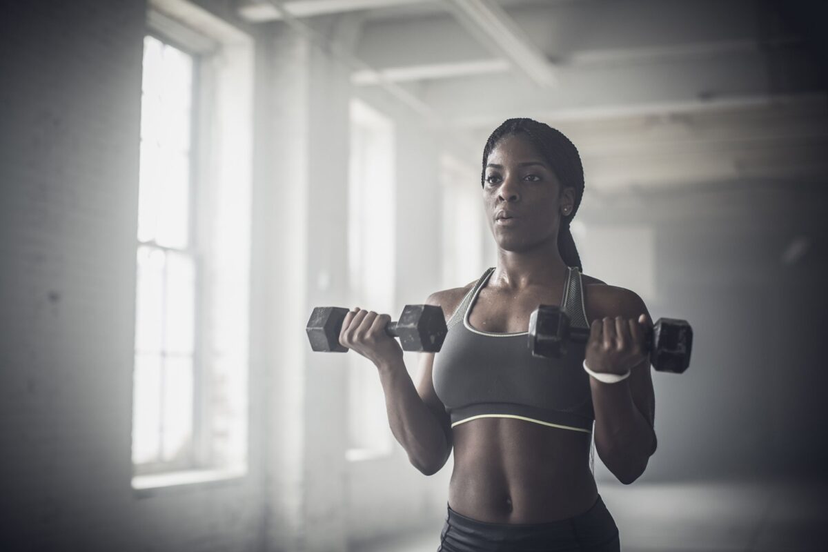 A woman is holding two dumbbells in her hands.